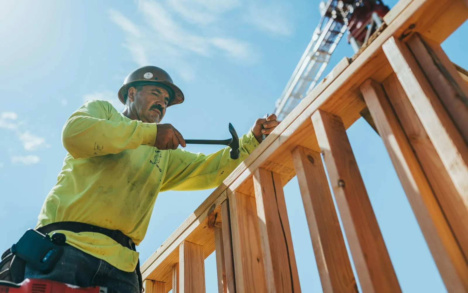 Ridgeline crew member framing a roof against a blue sky