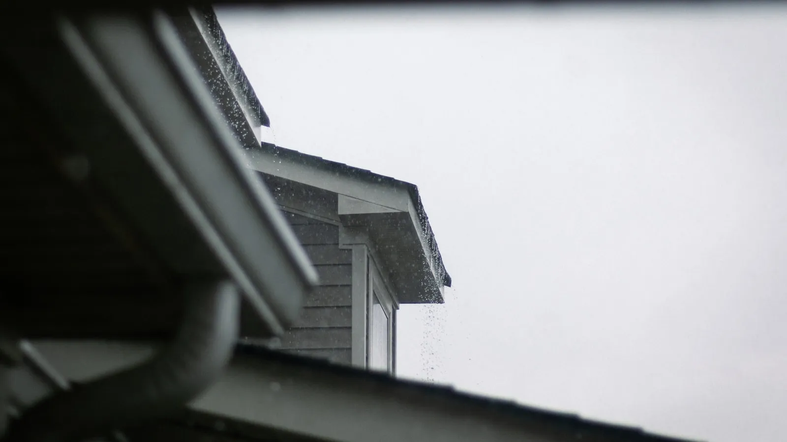 Rain running off a shingle roof edge into a gutter