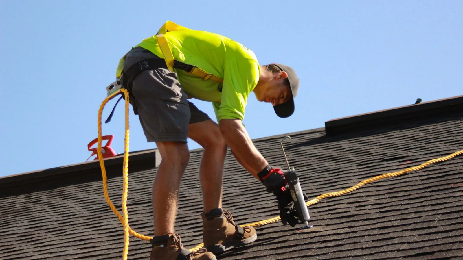 Roofer nailing architectural shingles on a residential roof